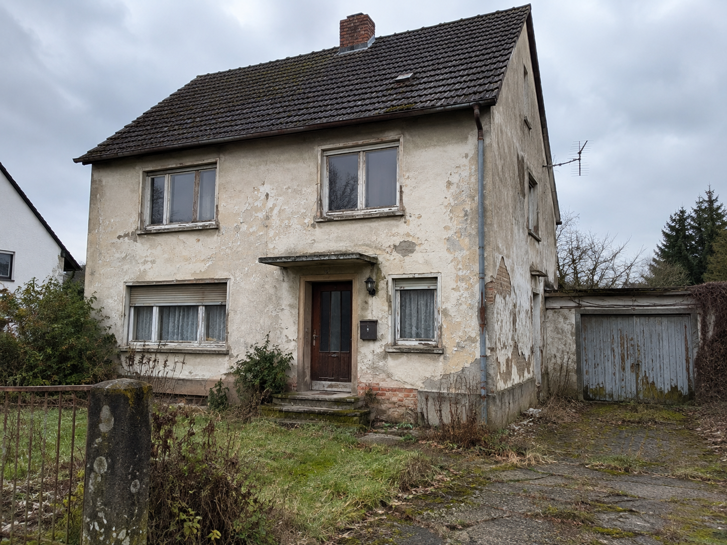 Vorher: unrenoviertes Haus mit rissiger, bewachsener Fassade